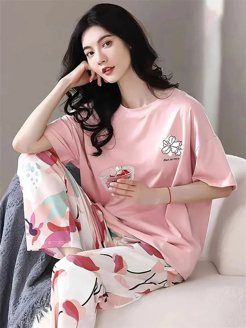 Woman wearing a pink pajama set with floral pants, sitting on a couch.