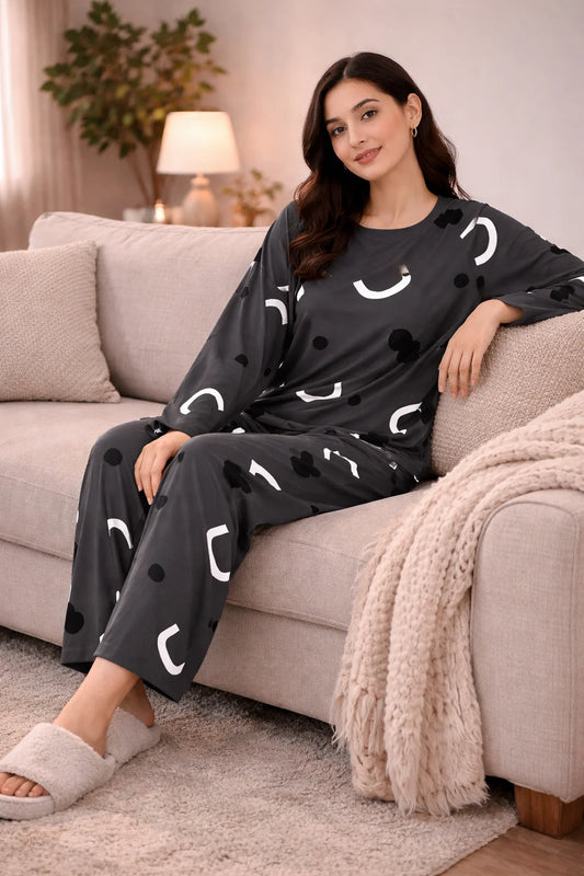 Woman wearing a black outfit with white patterns sitting on a couch in a cozy living room.