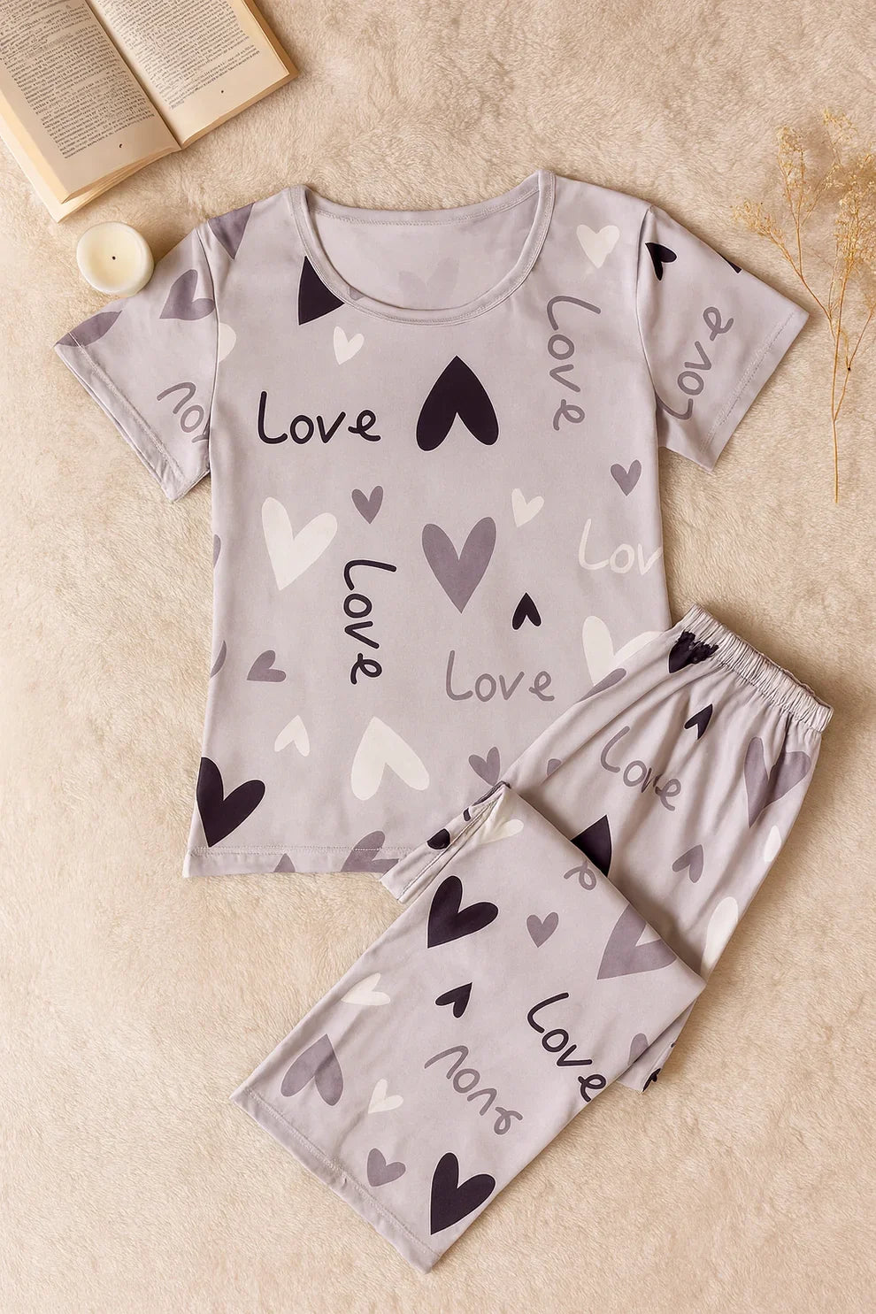 Children's pajama set with 'love' and heart patterns on a beige surface.