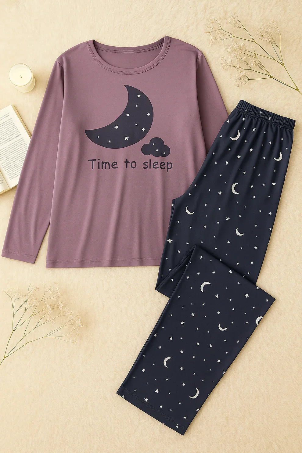 Purple long-sleeve top with moon and cloud design and navy pants with celestial pattern on a beige background.