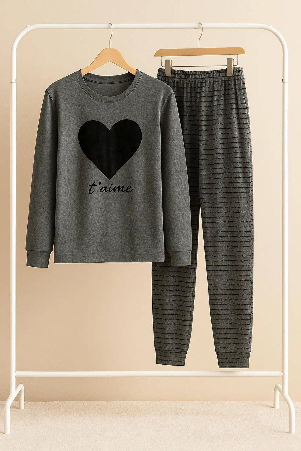 Gray sweatshirt with heart design and text, paired with striped pants on a rack.