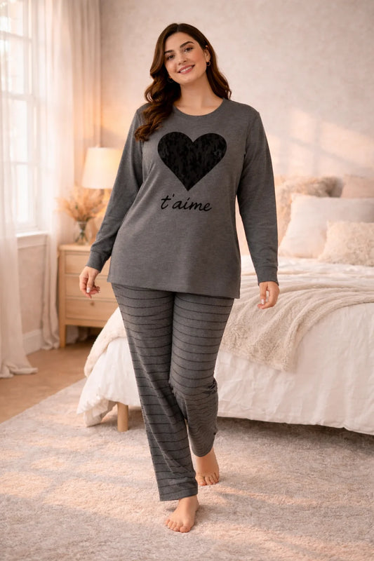 Woman wearing a gray pajama set with a heart design in a bedroom.