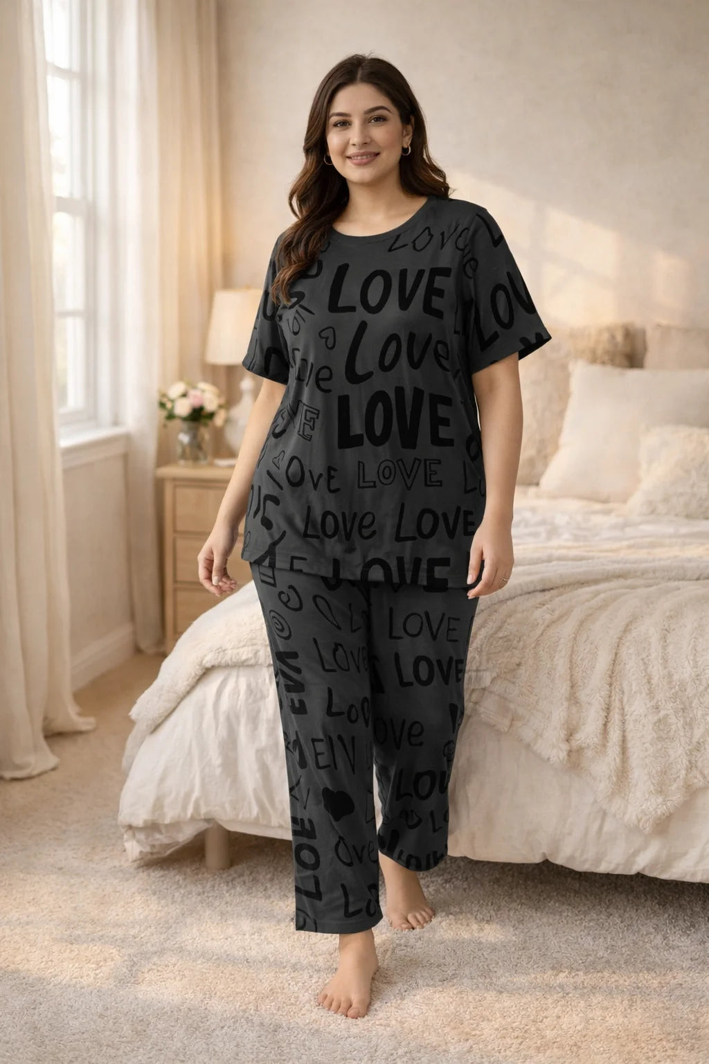 Woman wearing a black 'LOVE' pajama set in a bedroom.
