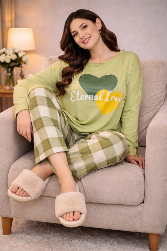 Woman wearing a green 'Eternal Love' shirt and plaid pants sitting on a couch.