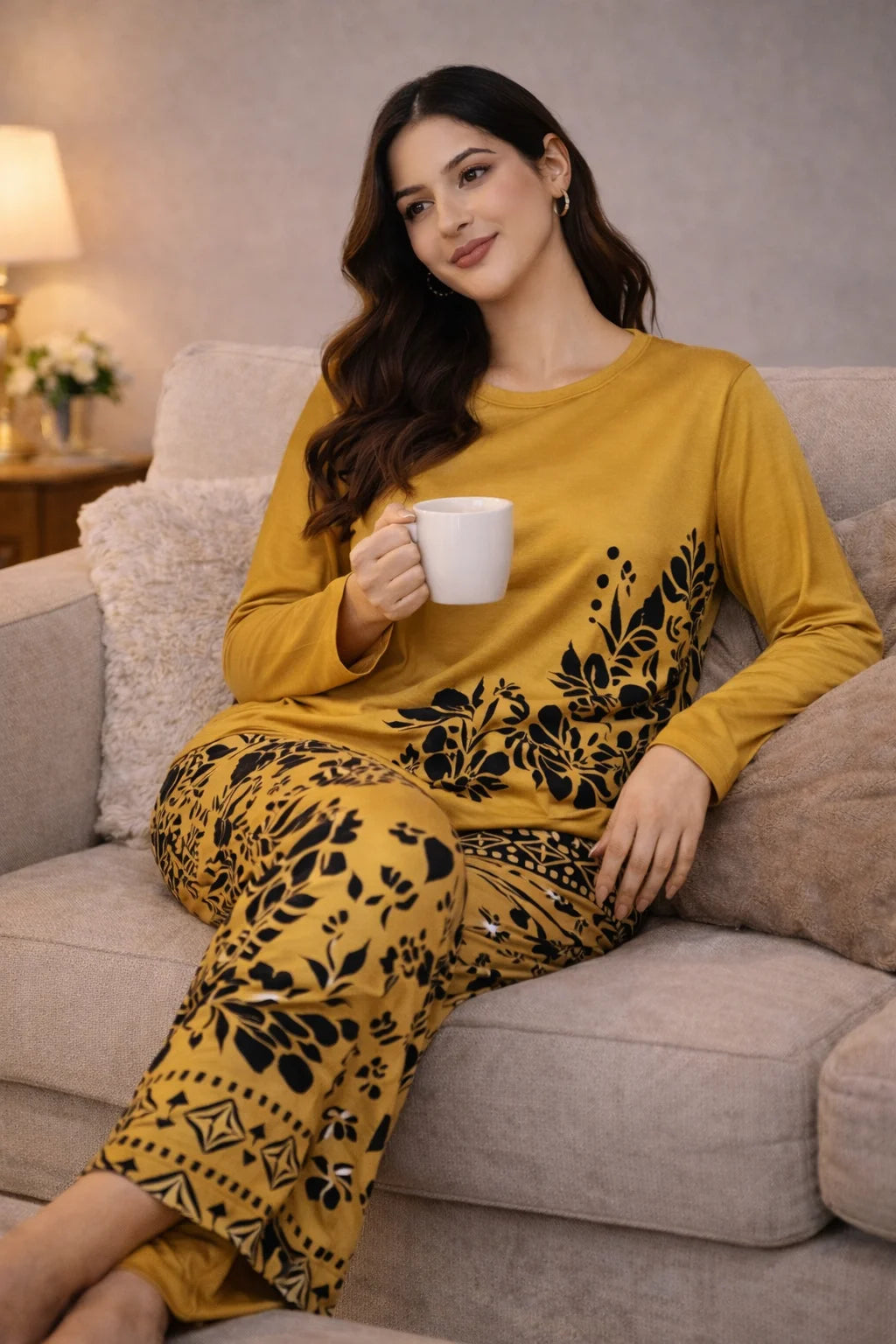 Woman in yellow pajama set holding a white mug on a couch