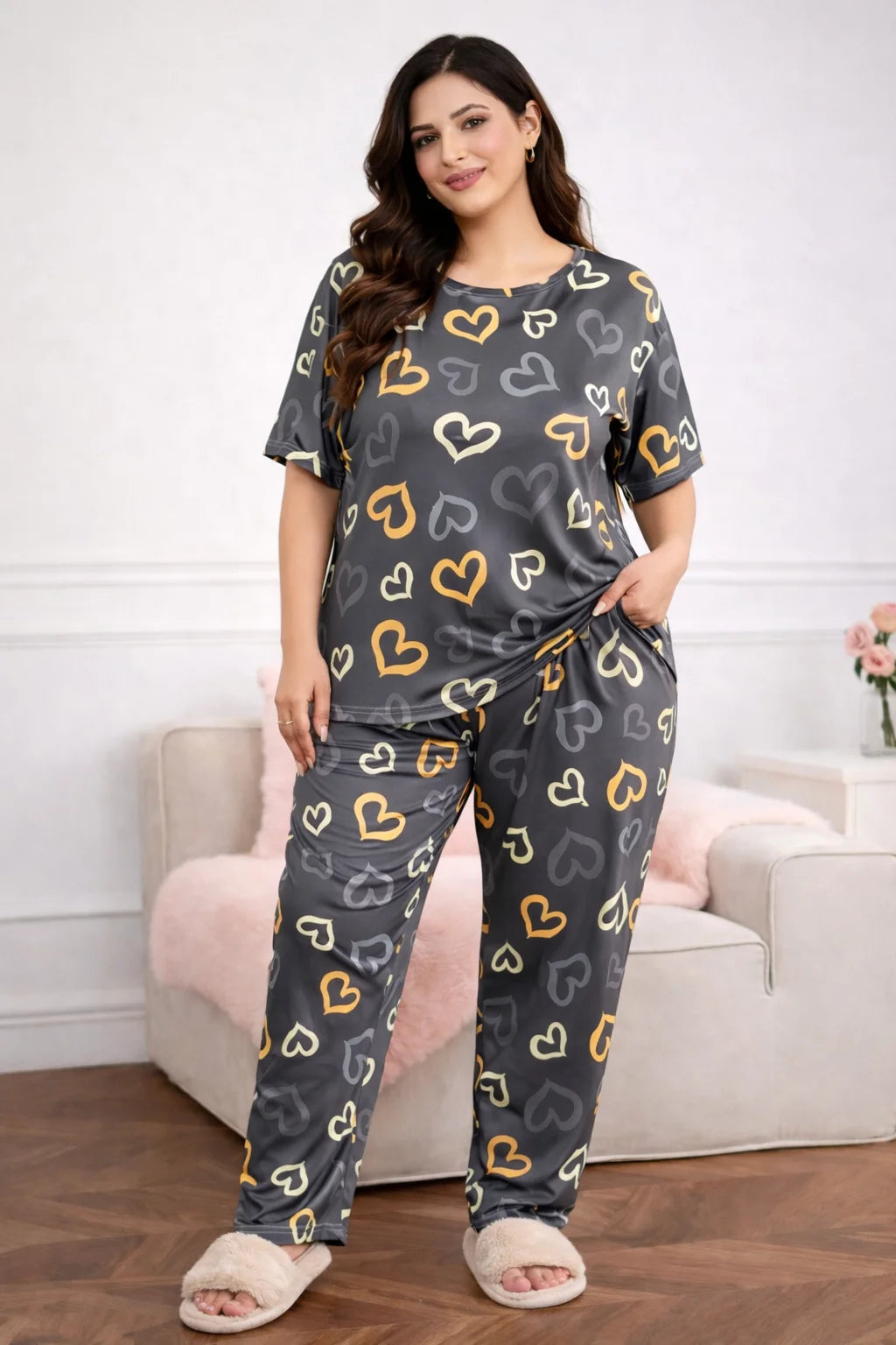 Woman wearing a heart-patterned pajama set in a living room.