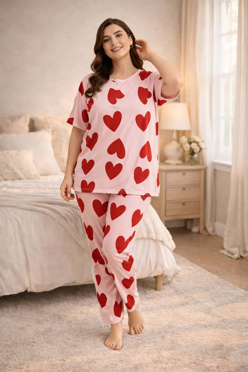 Woman wearing a heart-patterned pajama set in a bedroom.