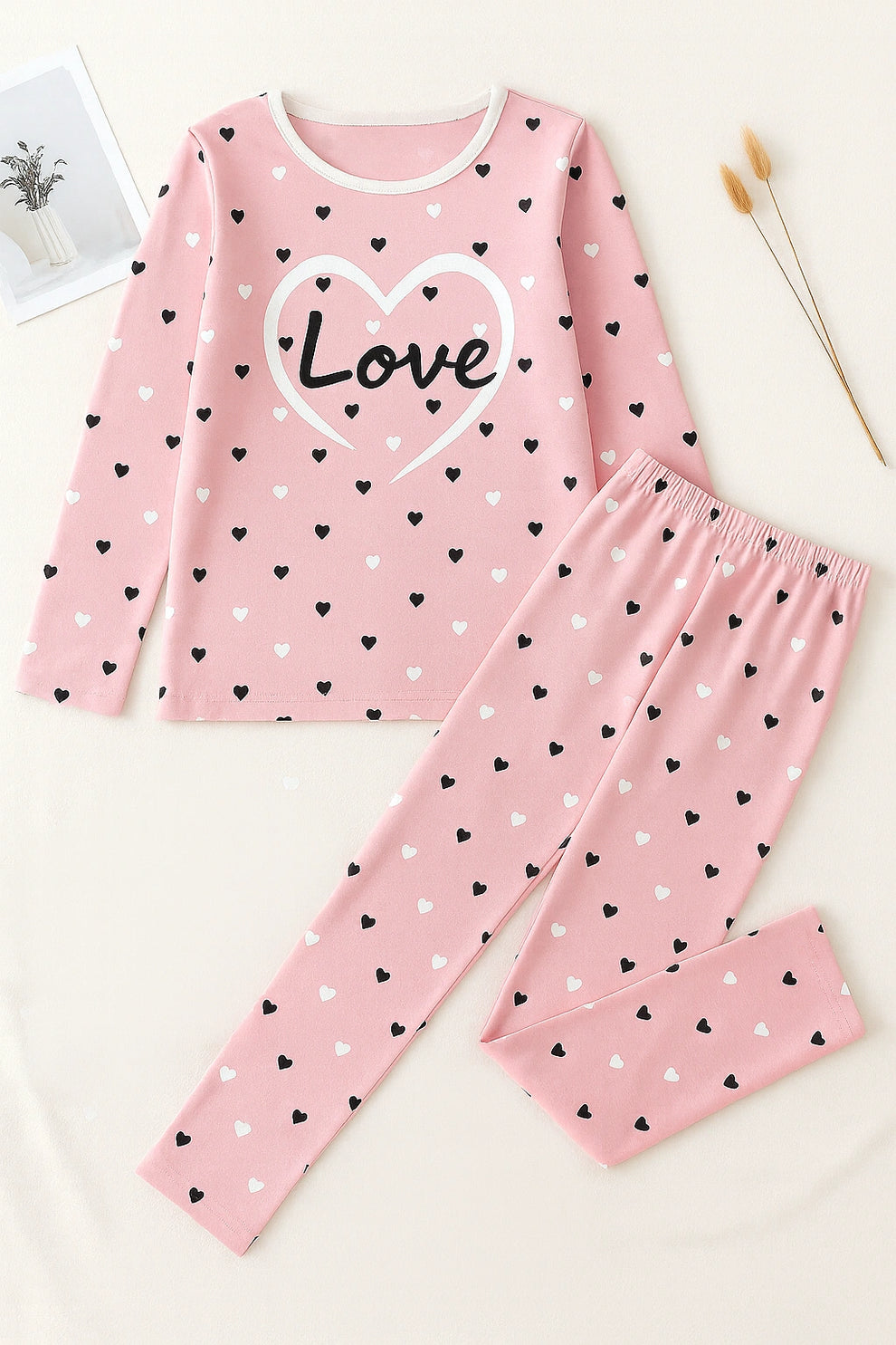 Pink pajama set with heart patterns and 'Love' text on a white background