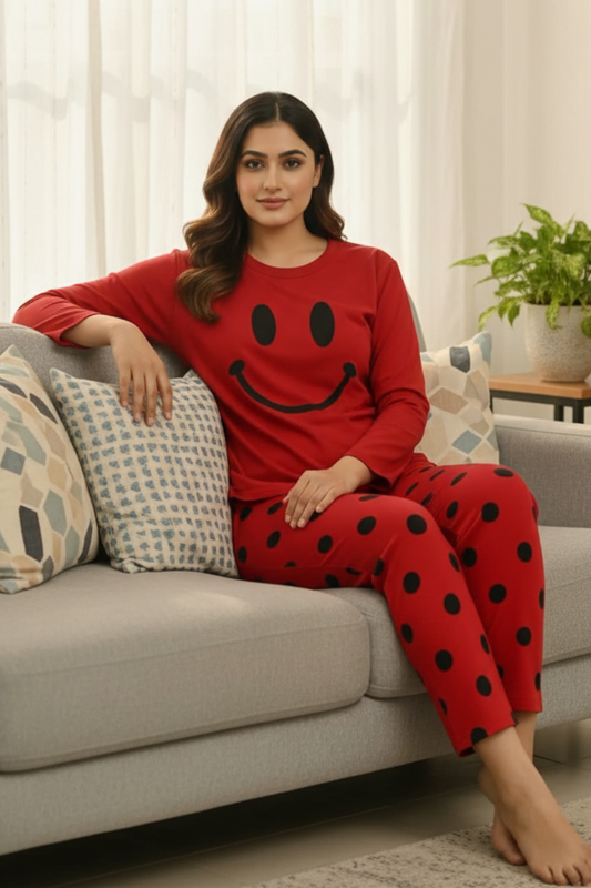 Woman wearing a red smiley face pajama set sitting on a couch.