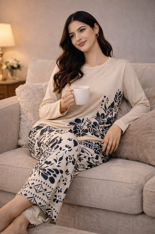Woman sitting on a couch holding a mug, wearing a patterned outfit.