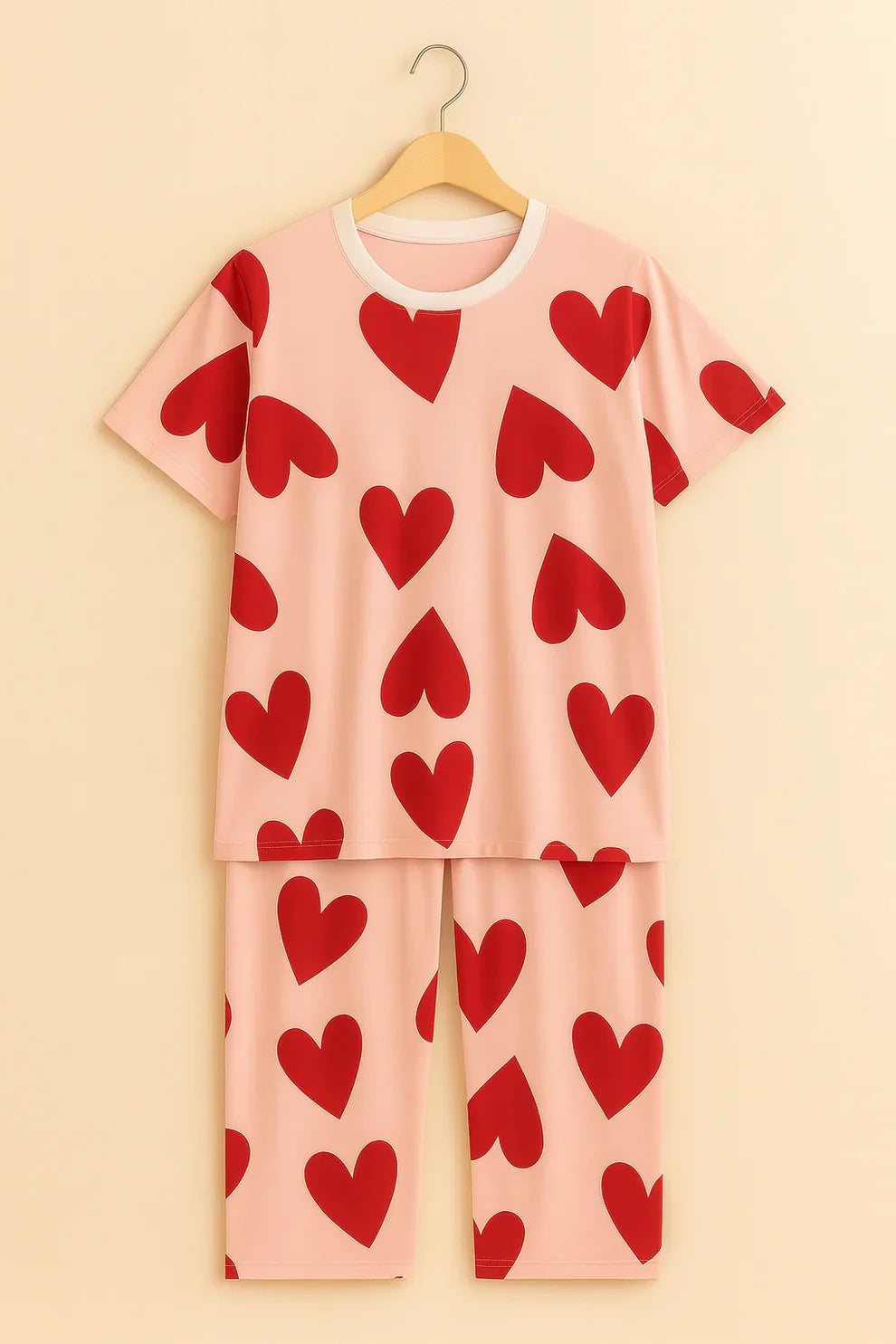 Pink pajama set with red heart patterns on a beige background