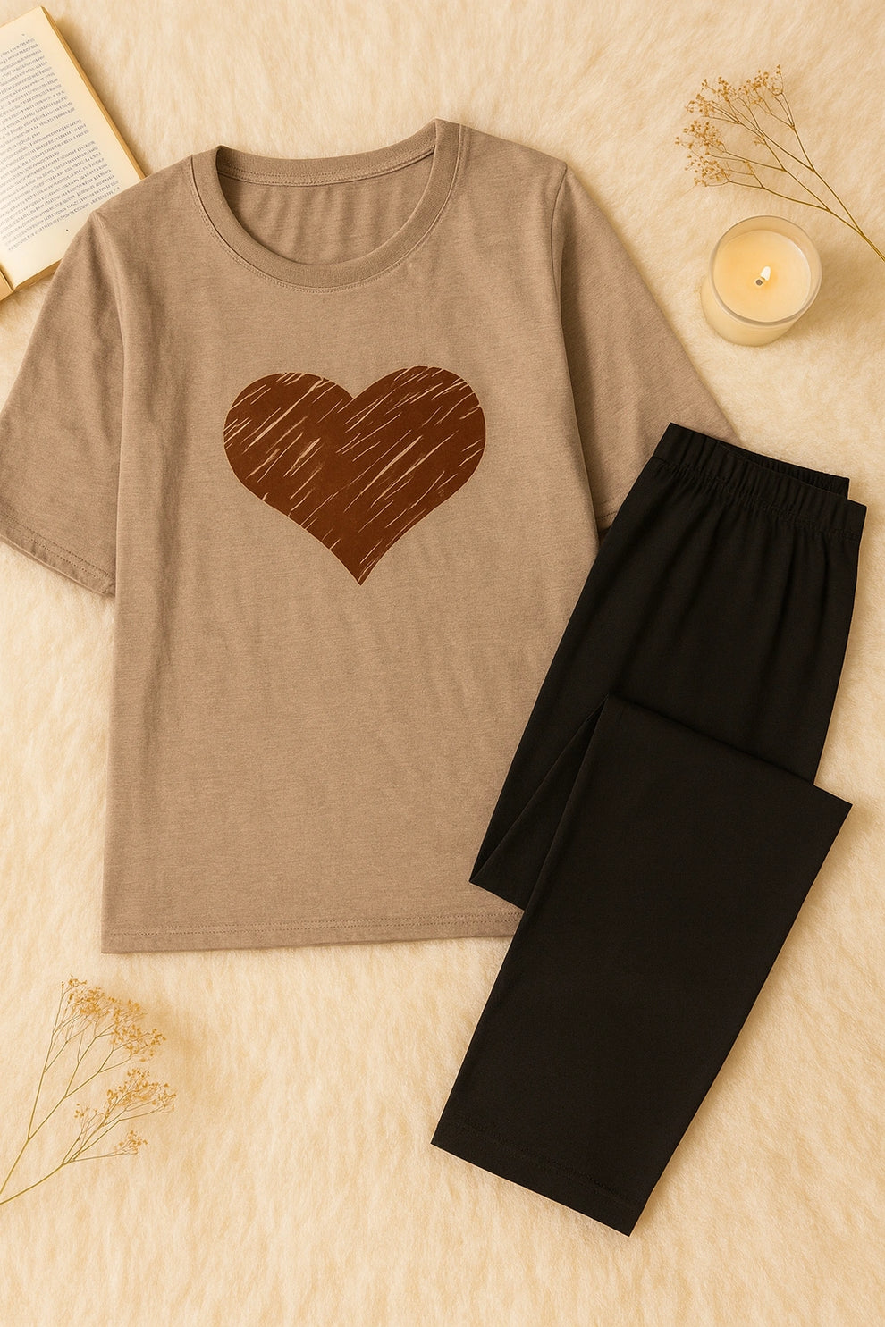 Brown t-shirt with a heart design and black pants on a beige surface.