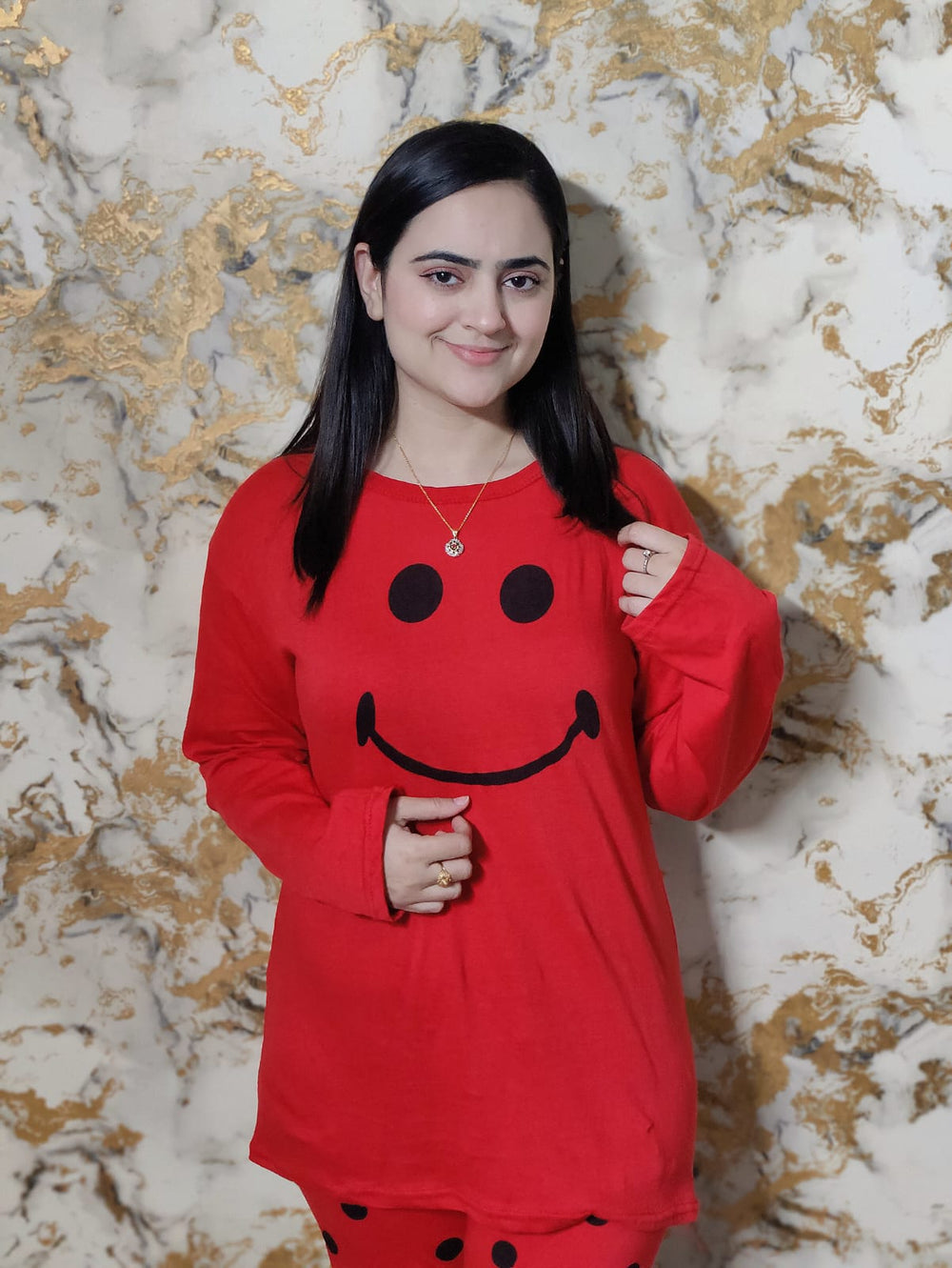 Woman wearing a red outfit with smiley face design against a marble background