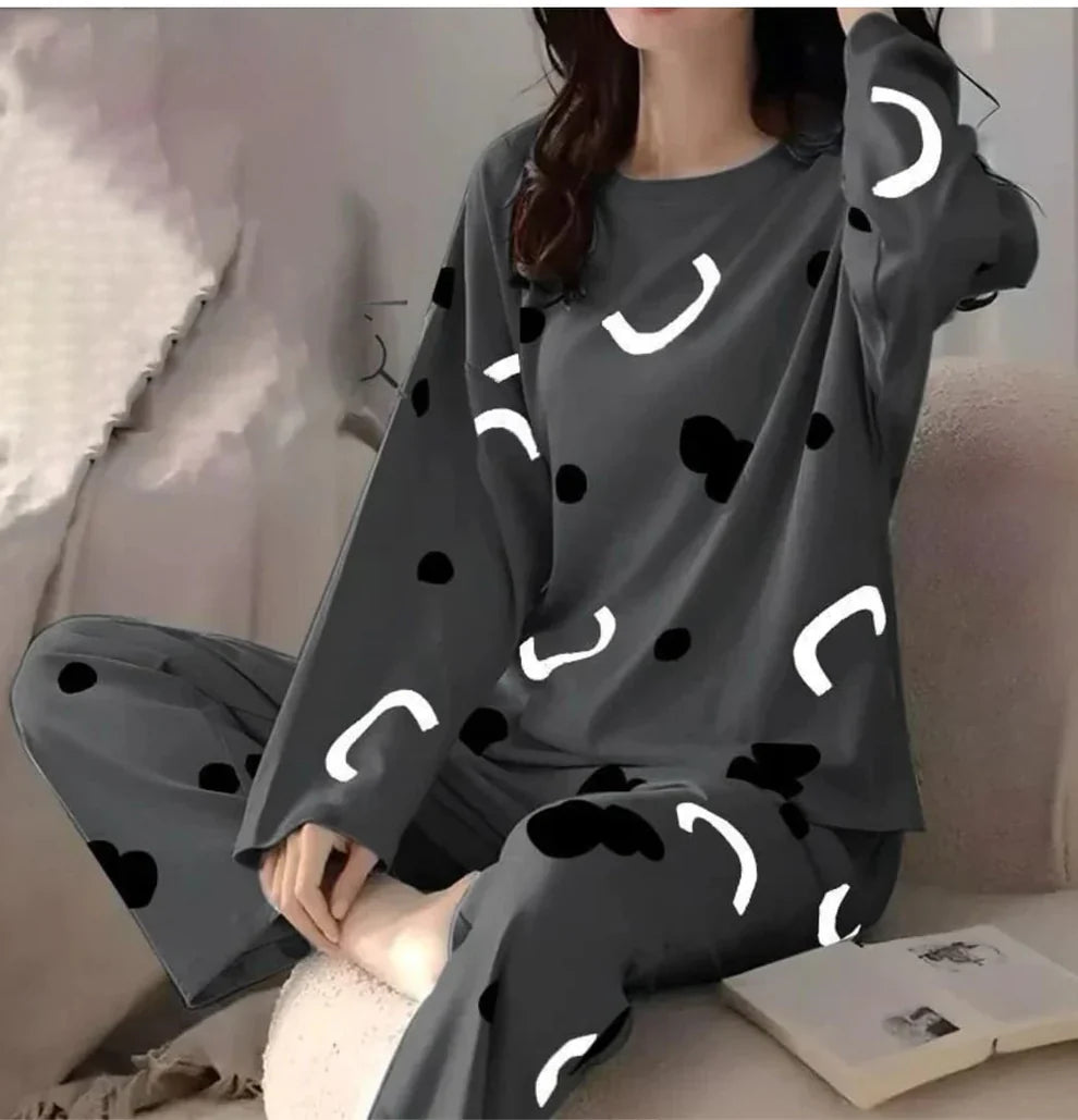 Person wearing a dark gray pajama set with white abstract patterns on a light pink couch.